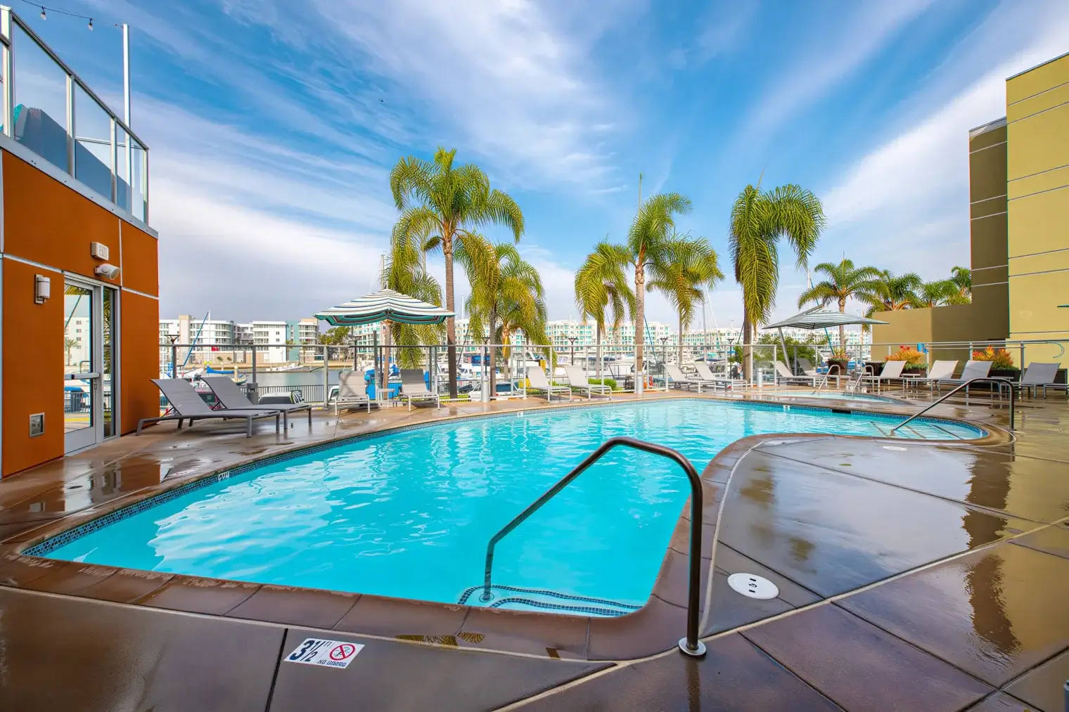 Harborside Marina Bay resort-style swimming pool surrounded by palm trees and lounge seating